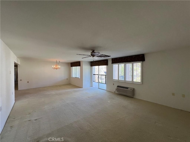 unfurnished living room featuring ceiling fan with notable chandelier, a wall mounted AC, and light colored carpet