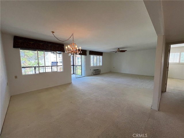 unfurnished room with light carpet, a wall unit AC, and ceiling fan with notable chandelier