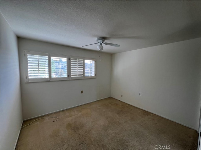 unfurnished room featuring a ceiling fan, light colored carpet, and a textured ceiling