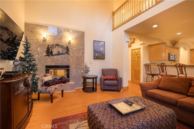 living room with light hardwood / wood-style floors, a multi sided fireplace, and a towering ceiling