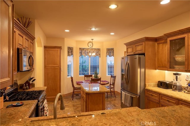 kitchen featuring light stone countertops, stainless steel appliances, a chandelier, a center island, and hanging light fixtures