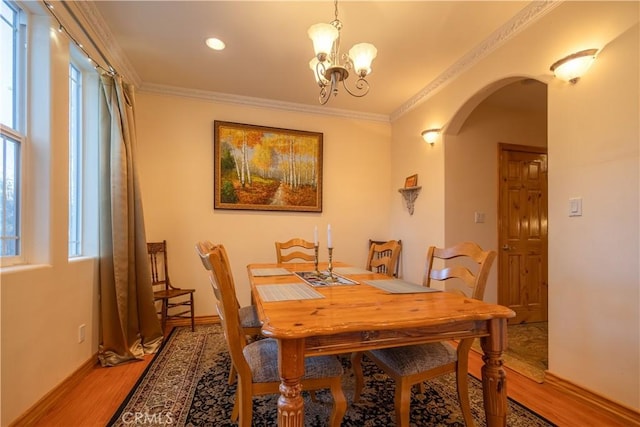 dining space with a chandelier, wood-type flooring, and ornamental molding