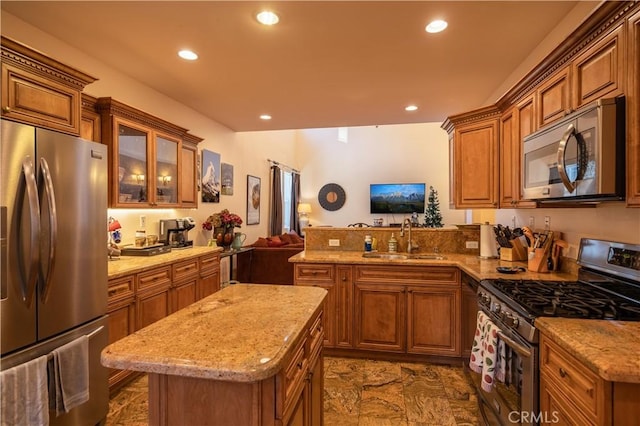 kitchen featuring sink, light stone countertops, a kitchen island, kitchen peninsula, and stainless steel appliances