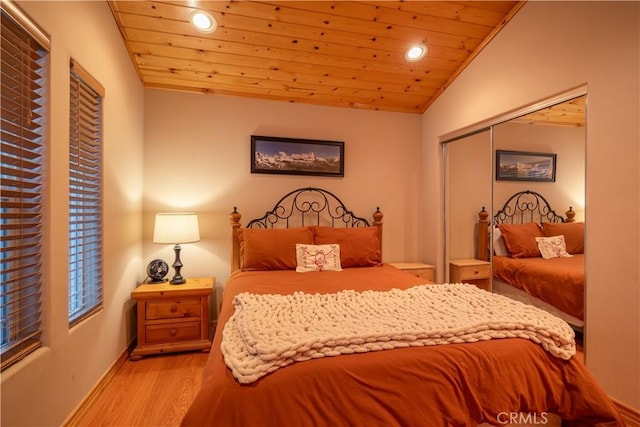 bedroom with lofted ceiling, a closet, wood ceiling, and light hardwood / wood-style flooring