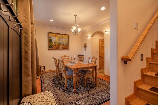 dining space with hardwood / wood-style flooring, a notable chandelier, and crown molding