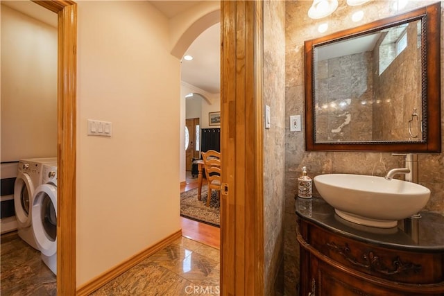 bathroom with washing machine and dryer, crown molding, vanity, and tile walls