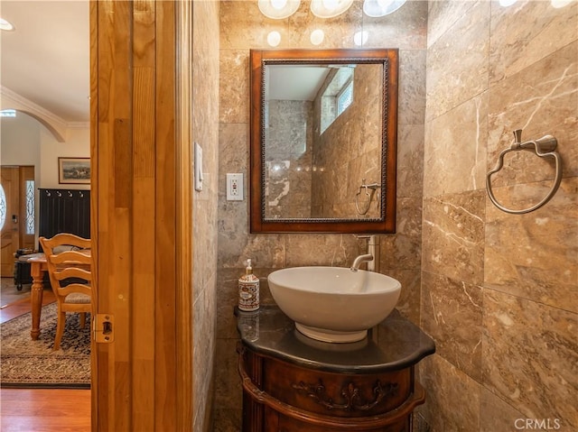 bathroom featuring hardwood / wood-style floors, vanity, crown molding, and tile walls