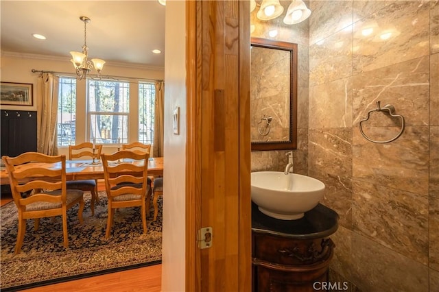 bathroom featuring vanity, crown molding, hardwood / wood-style flooring, tile walls, and a notable chandelier