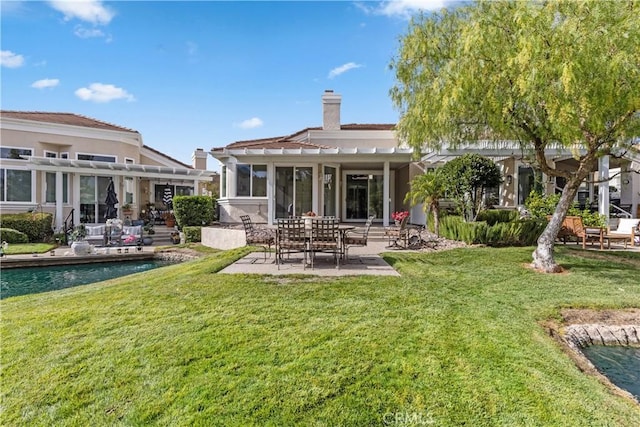 rear view of house with a sunroom, a patio, and a lawn