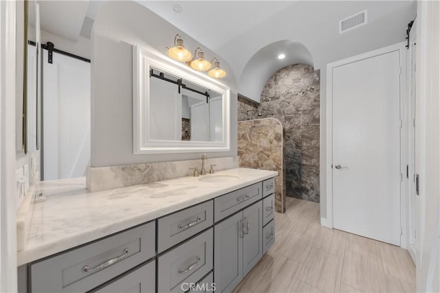 bathroom with a shower, vanity, and tile walls