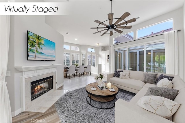 living room with a fireplace, light wood-type flooring, and ceiling fan