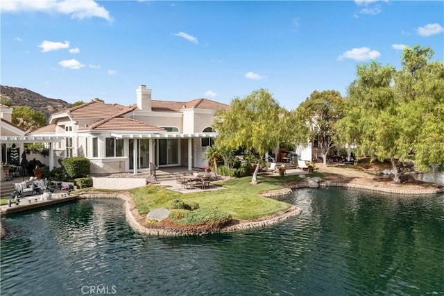 back of property featuring a pergola, a water view, and a patio area