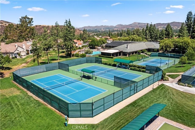 view of tennis court with a mountain view and a yard