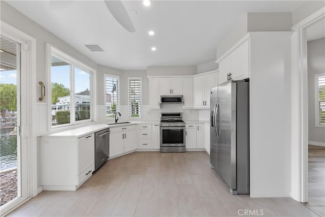 kitchen with sink, white cabinets, light hardwood / wood-style floors, and appliances with stainless steel finishes