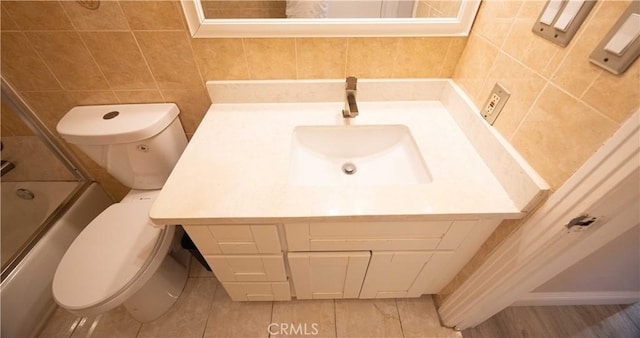 full bathroom with decorative backsplash, vanity, toilet, and bath / shower combo with glass door