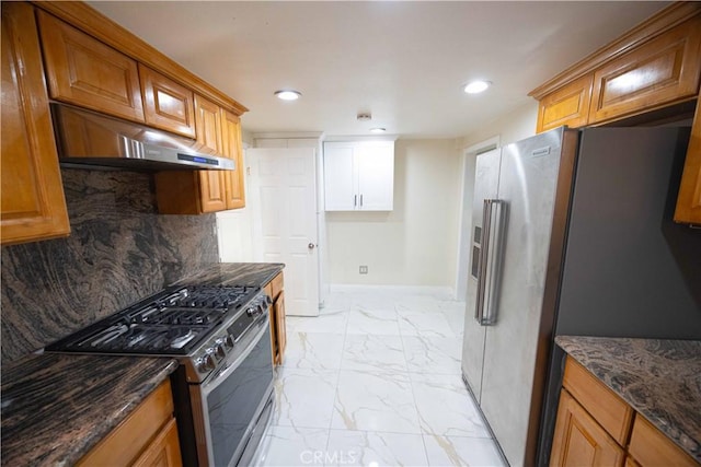 kitchen featuring ventilation hood, backsplash, stainless steel appliances, and dark stone counters