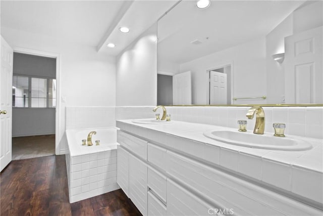 bathroom featuring hardwood / wood-style floors, vanity, and tiled bath