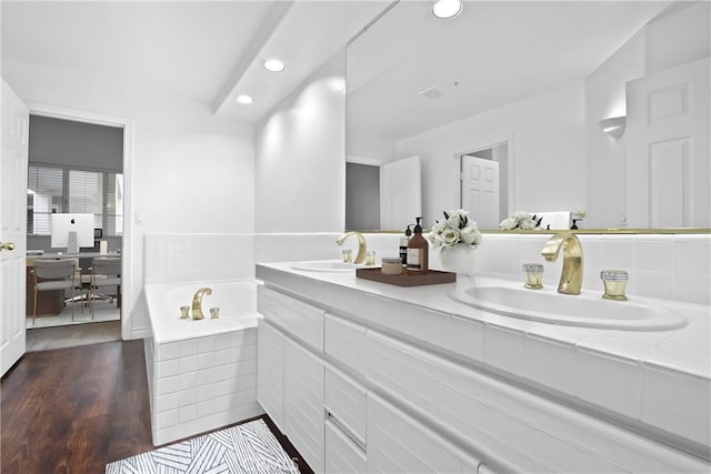 bathroom featuring vanity, wood-type flooring, and tiled bath