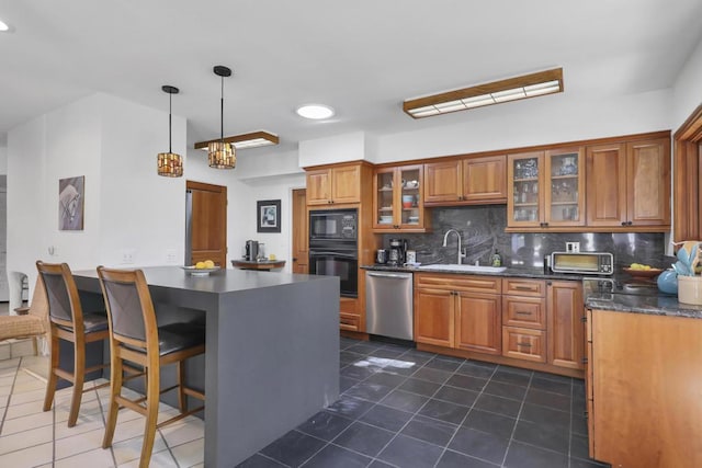 kitchen with hanging light fixtures, black appliances, decorative backsplash, dark tile patterned flooring, and sink