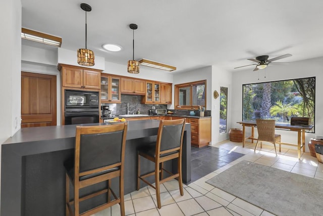 kitchen featuring black appliances, hanging light fixtures, light tile patterned floors, ceiling fan, and backsplash