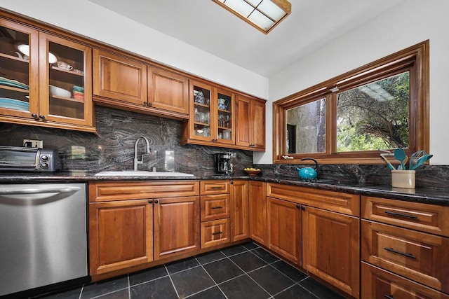 kitchen featuring dishwasher, dark tile patterned flooring, dark stone countertops, and sink