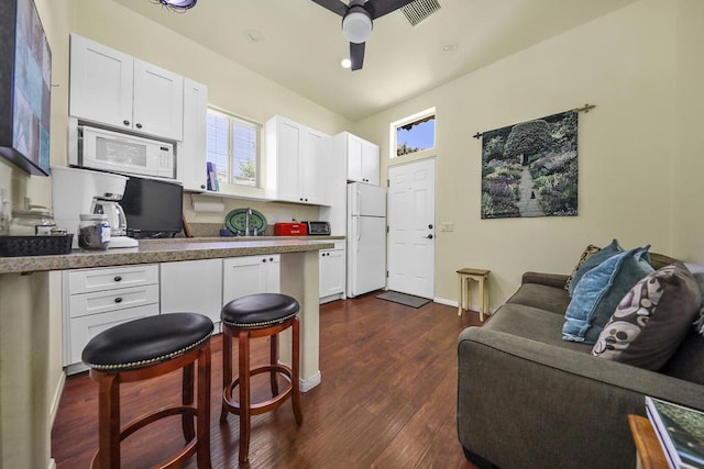 kitchen with white appliances, white cabinetry, plenty of natural light, and dark wood-type flooring