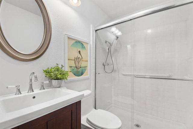 bathroom featuring vanity, a shower with door, and toilet