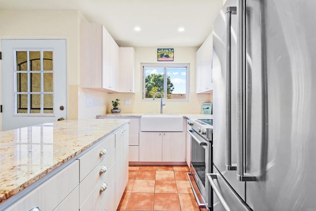 kitchen featuring light stone counters, light tile patterned floors, backsplash, appliances with stainless steel finishes, and a sink