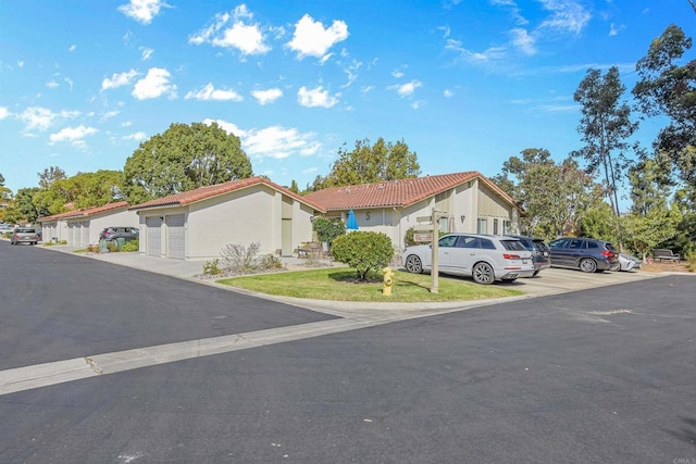 view of front of house with a garage, a tiled roof, a residential view, and stucco siding