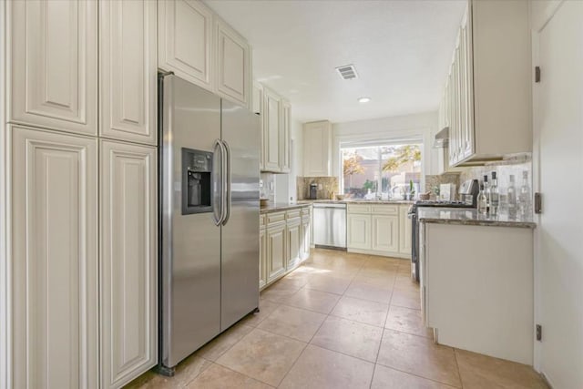 kitchen featuring tasteful backsplash, sink, light tile patterned floors, and stainless steel appliances