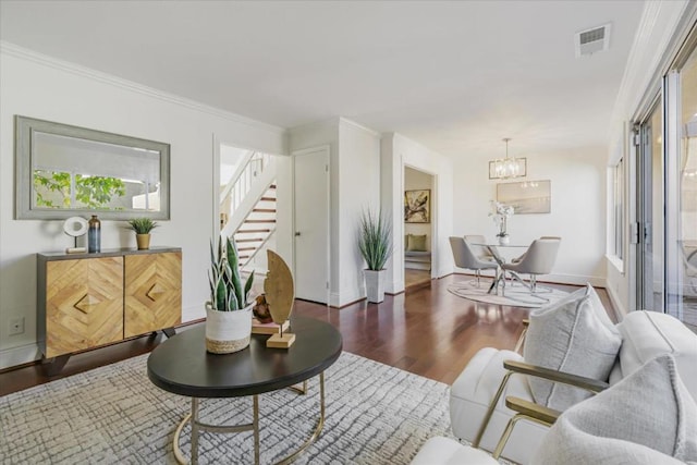 living room with dark hardwood / wood-style floors, an inviting chandelier, and crown molding