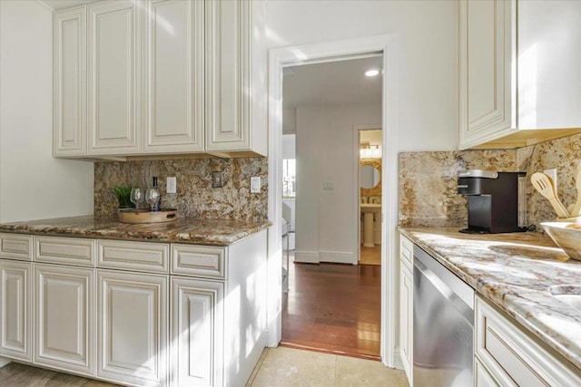 kitchen featuring stainless steel dishwasher, stone countertops, decorative backsplash, and light tile patterned floors