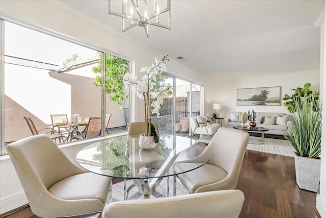 dining area with a chandelier, wood-type flooring, and ornamental molding