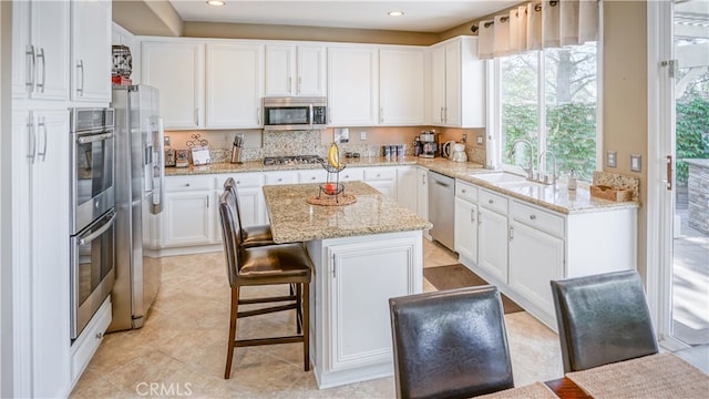 kitchen featuring appliances with stainless steel finishes, a center island, sink, and plenty of natural light