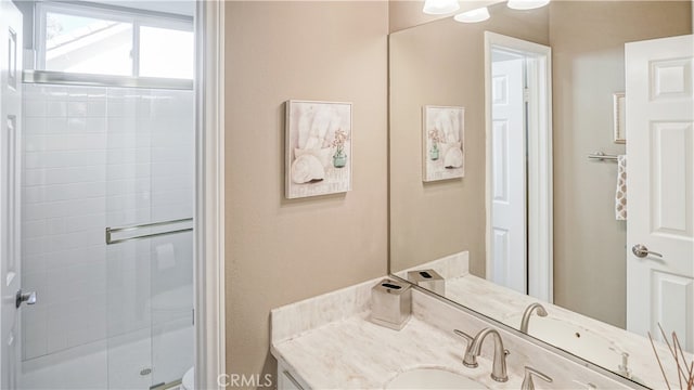 bathroom featuring a shower with door and vanity