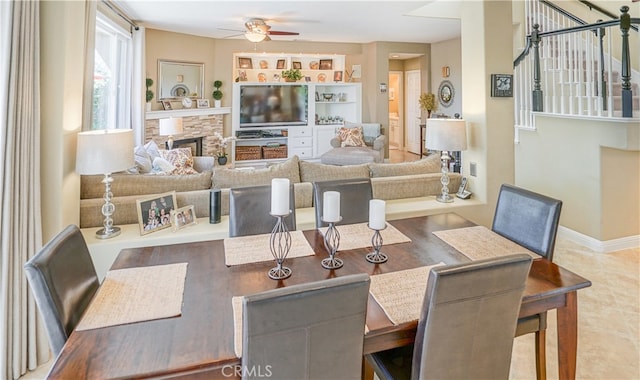 tiled dining area with ceiling fan and a fireplace