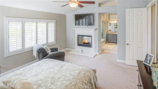 carpeted bedroom with connected bathroom, lofted ceiling, a multi sided fireplace, and ceiling fan