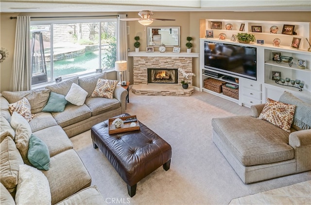 carpeted living room featuring ceiling fan and a fireplace