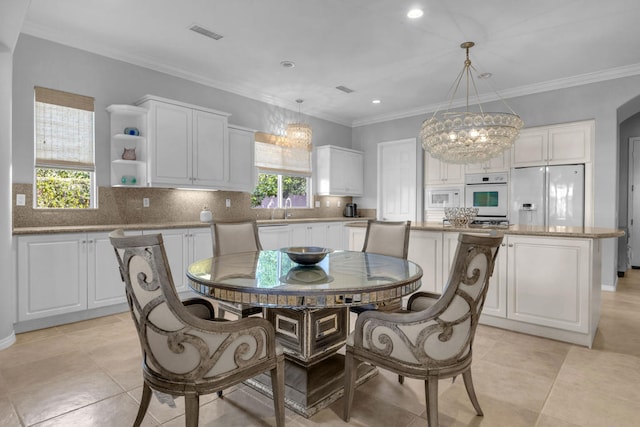 tiled dining area featuring sink, crown molding, and a chandelier