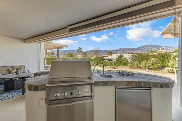 view of patio / terrace with a mountain view, sink, area for grilling, and exterior kitchen