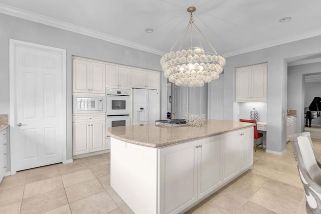 kitchen featuring white appliances, decorative light fixtures, a notable chandelier, white cabinets, and a center island