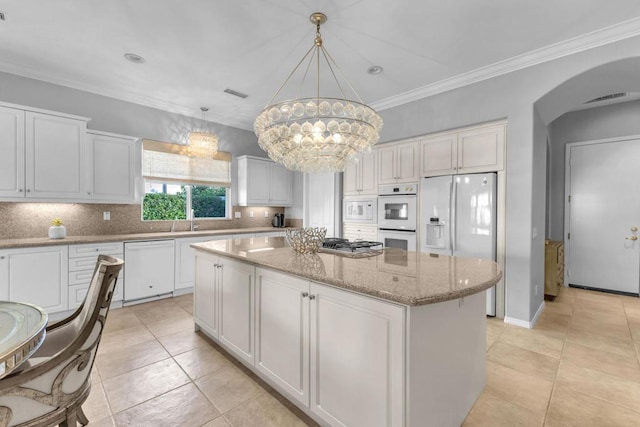 kitchen with white cabinets, white appliances, a kitchen island, and a notable chandelier