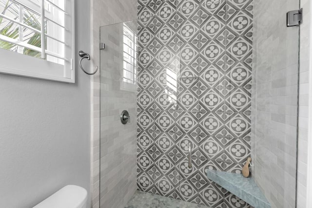 bathroom featuring plenty of natural light, an enclosed shower, and toilet