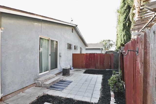 view of side of home with central AC unit and a patio