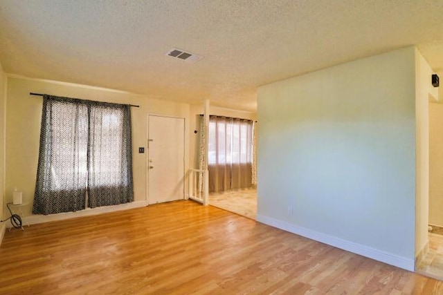 spare room with a textured ceiling and light wood-type flooring