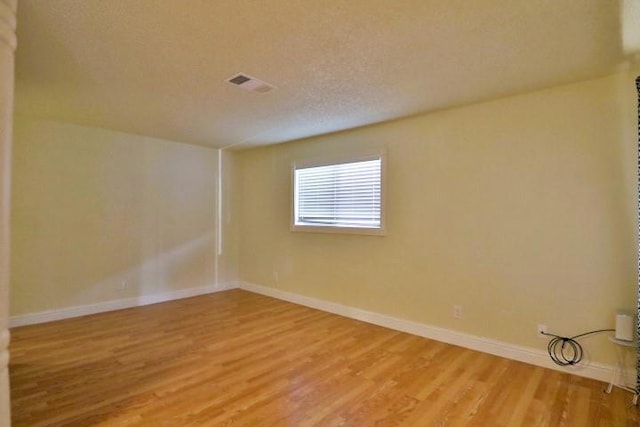 spare room featuring wood-type flooring and a textured ceiling