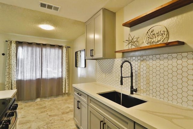 kitchen featuring stainless steel range with electric cooktop, sink, decorative backsplash, and gray cabinetry