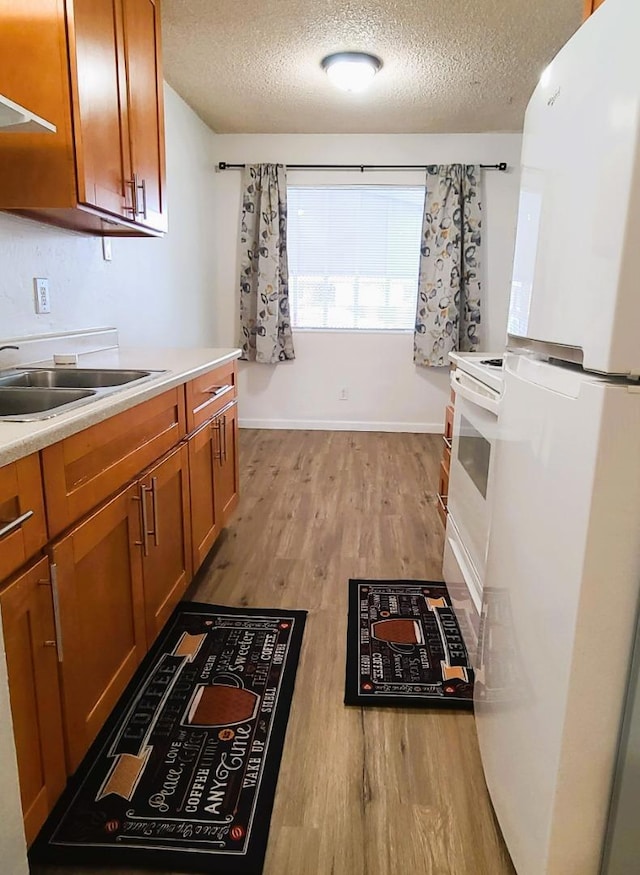 kitchen with white refrigerator, sink, light hardwood / wood-style floors, and a textured ceiling