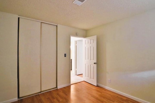 unfurnished bedroom with hardwood / wood-style flooring, a textured ceiling, and a closet