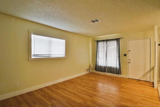 spare room featuring hardwood / wood-style floors and a textured ceiling